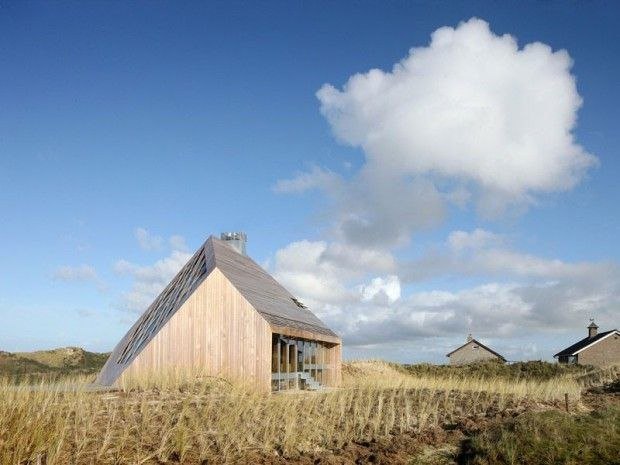 Maison de bois sur la dune, sous un grand ciel et un nuage blanc