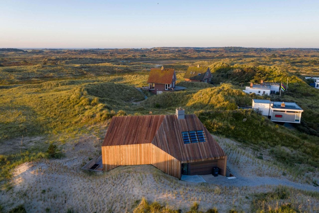 Vue aérienne des dunes au coucher du soleil : les maisons dispersées entre les oyats, la mer à l'horizon